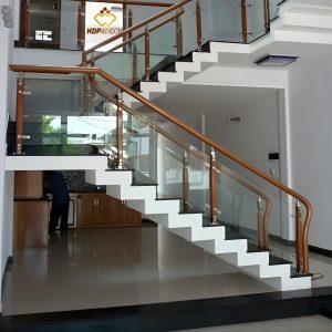 Mẫu cầu thang kính tay vịn gỗ tròn kết hợp trụ inox ốp gỗ độc đáo.