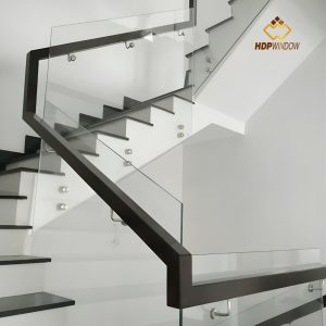 Minh họa mẫu cầu thang kính không trụ với tay vịn (gỗ hoặc inox) được bắt bên hông vách kính.